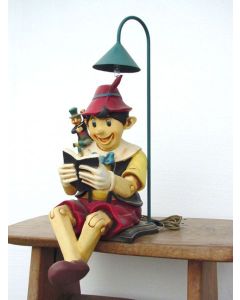 Pinocchio lesend mit Lampe lebensgroß